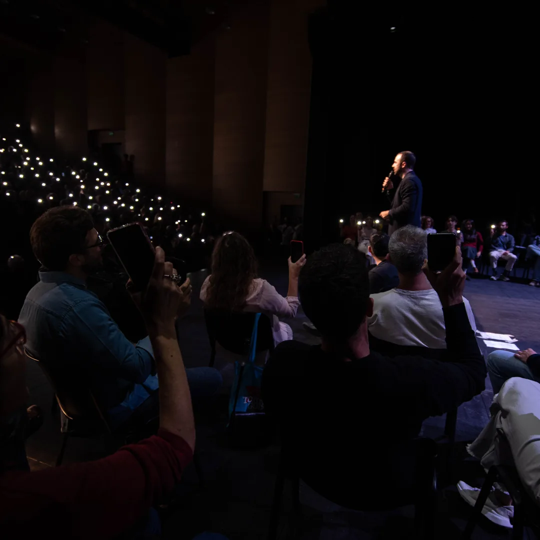 Tommaso Goisis sul palco del Teatro Elfo Puccini il 17 ottobre, davanti alla sala che lo ascolta con le luci dei telefoni accese